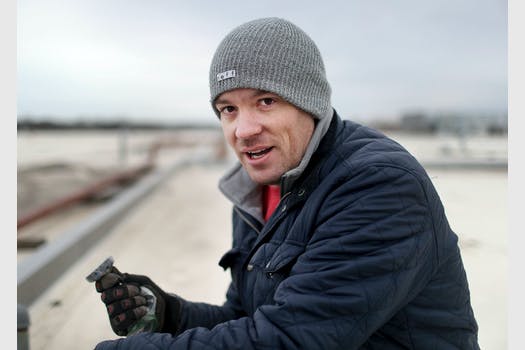 Scott Peterson holds a magnet up shilst sitting on the roof of a building